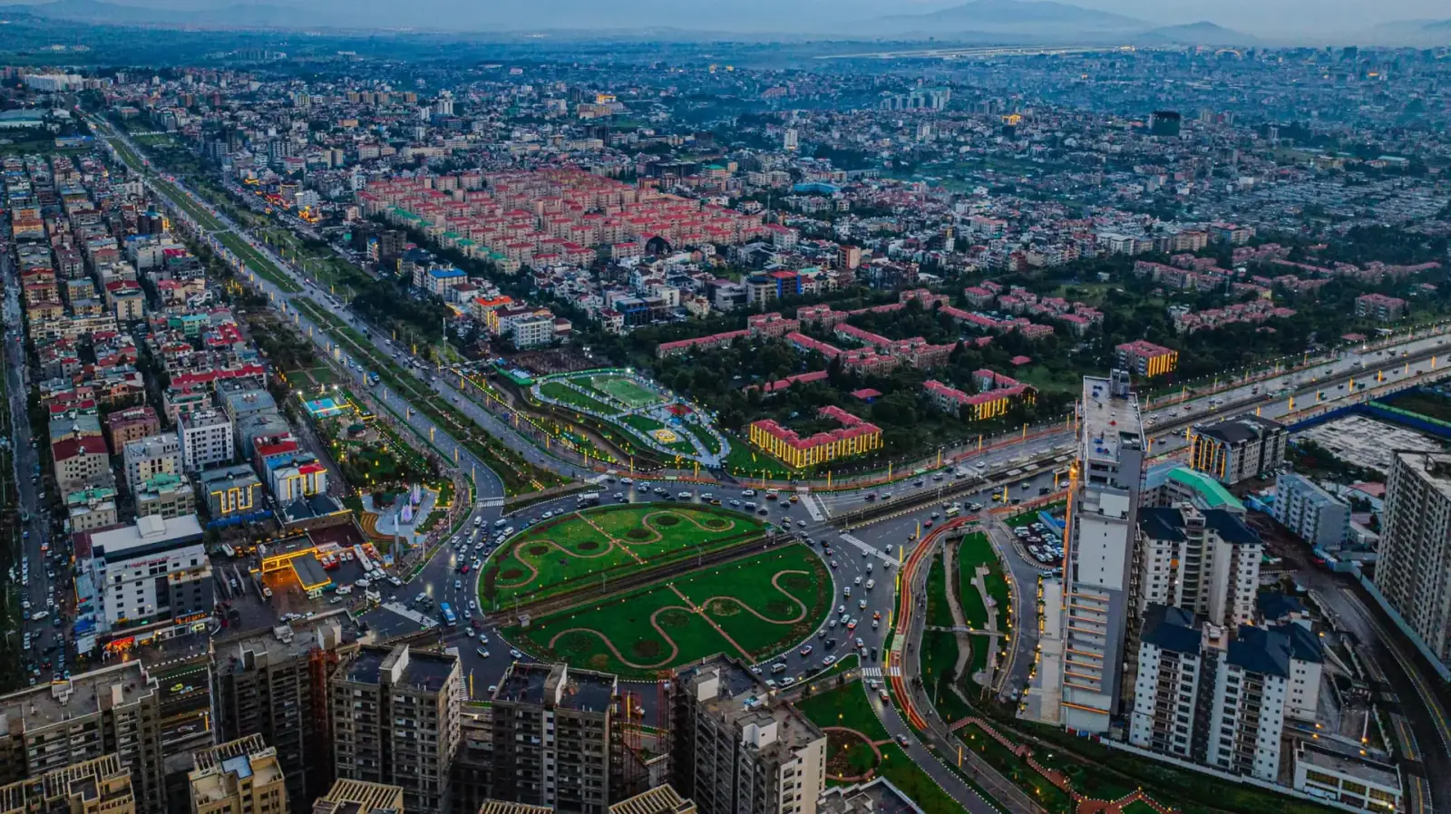 Aerial dusk view of Addis Ababa showing the city's roundabout, residential districts, and mountains in the distance