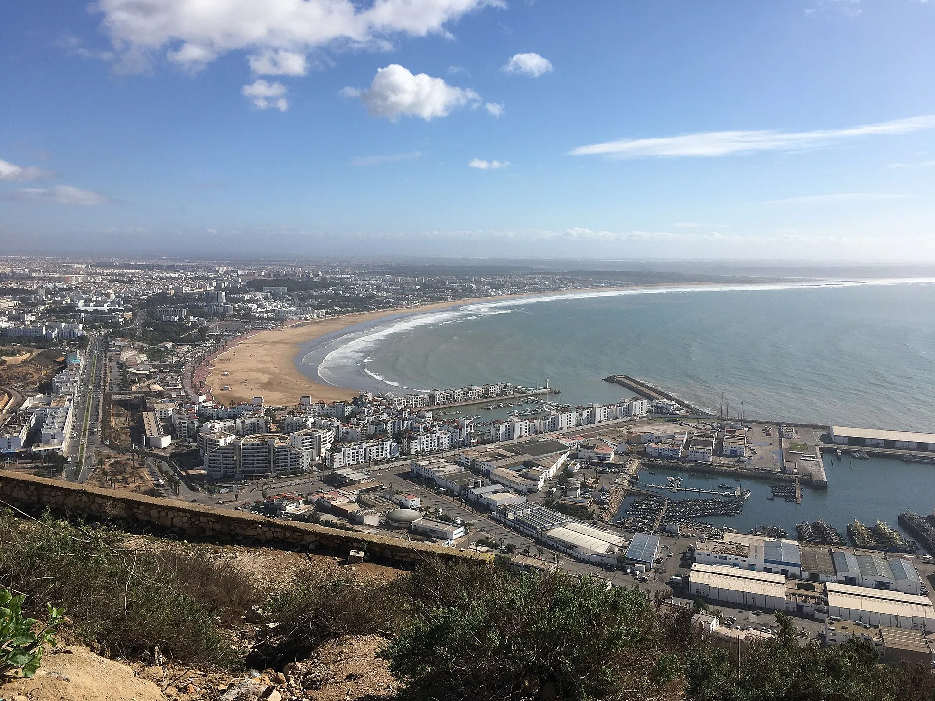 The sweeping crescent beach, marina and white low rise city of Agadir seen from the hilltop kasbah on a bright day