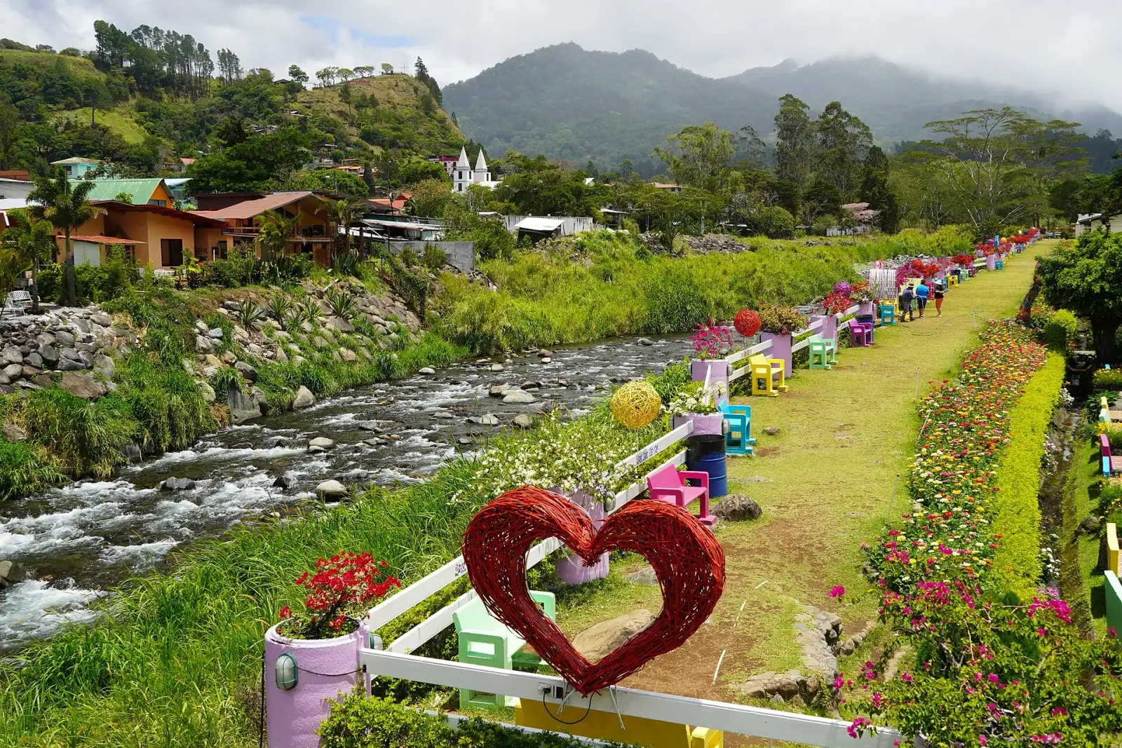 Caldera River and flower gardens at the bridge of Boquete, Panama, with the white church steeple and cloud-forest mountains behind