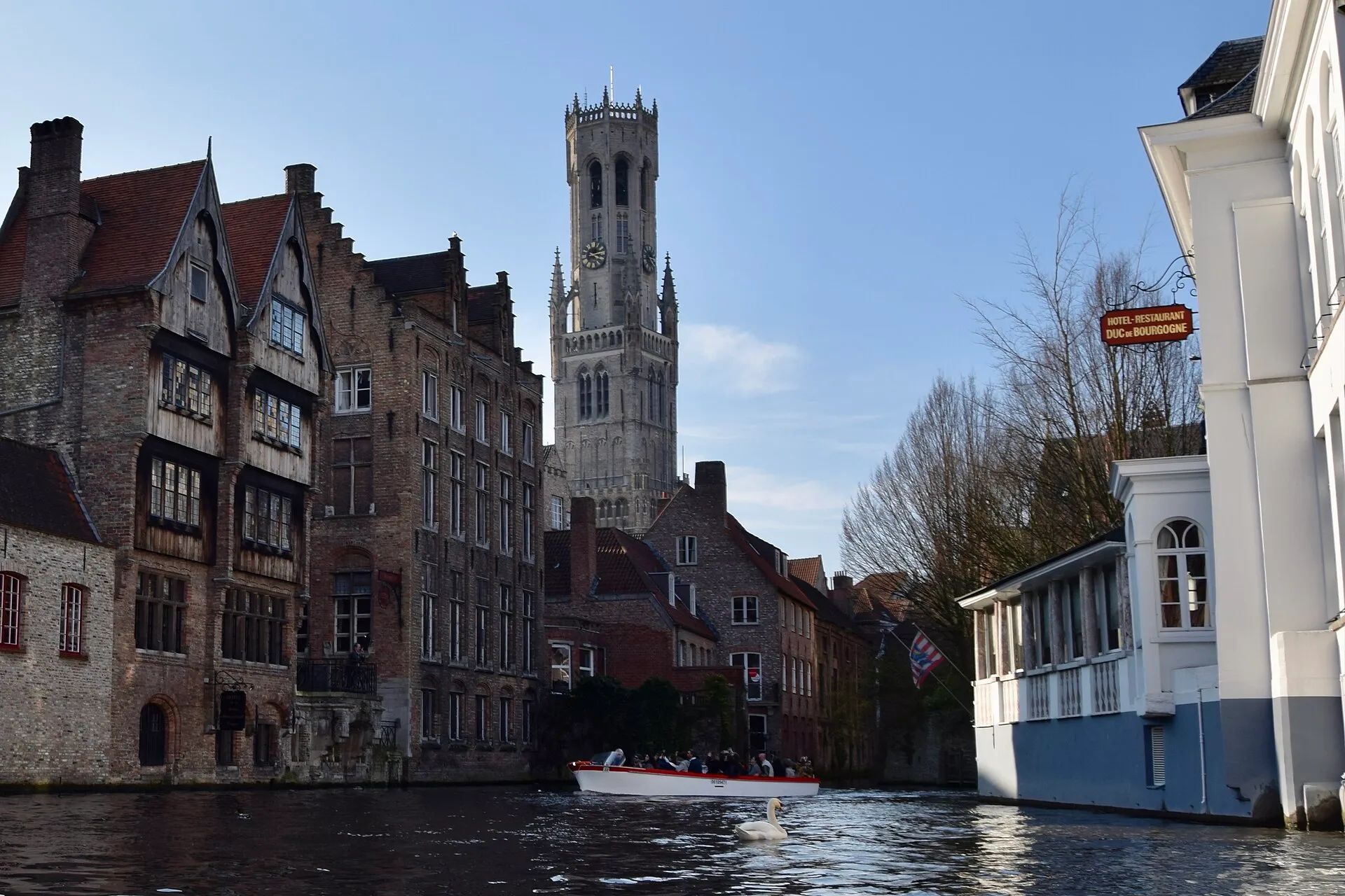 Rozenhoedkaai canal with the Belfry of Bruges rising above medieval step-gabled buildings, Bruges, Belgium