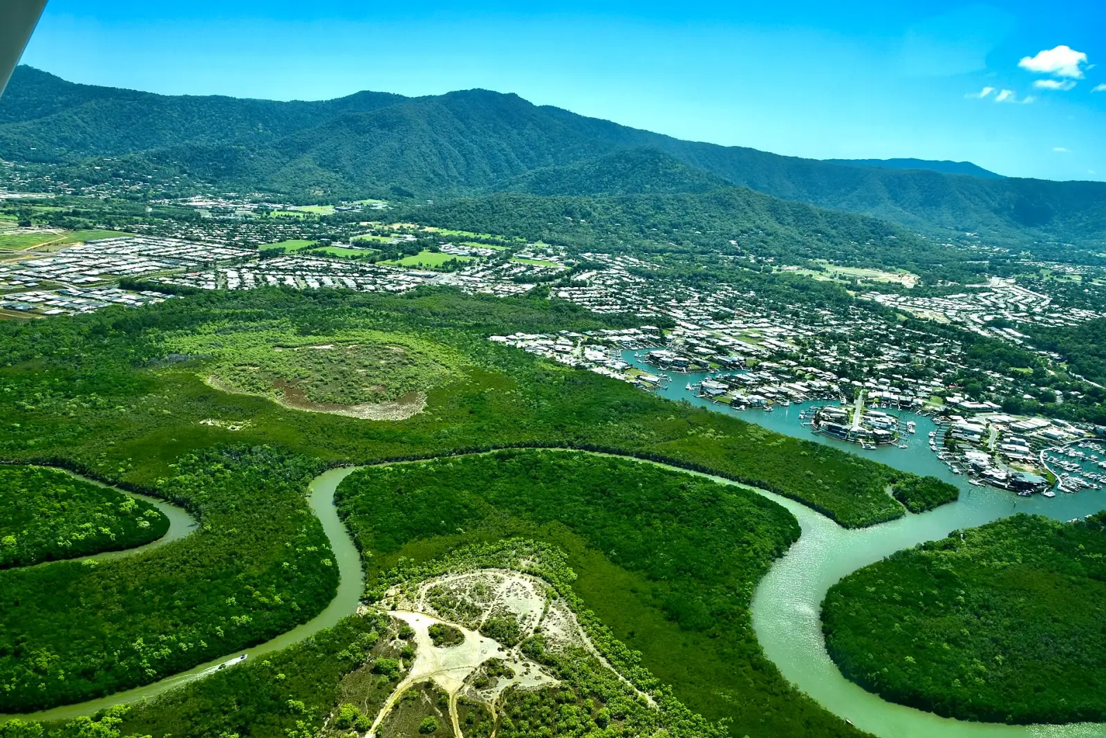 Aerial view of Cairns showing Trinity Inlet mangroves, city marina, and rainforest mountains