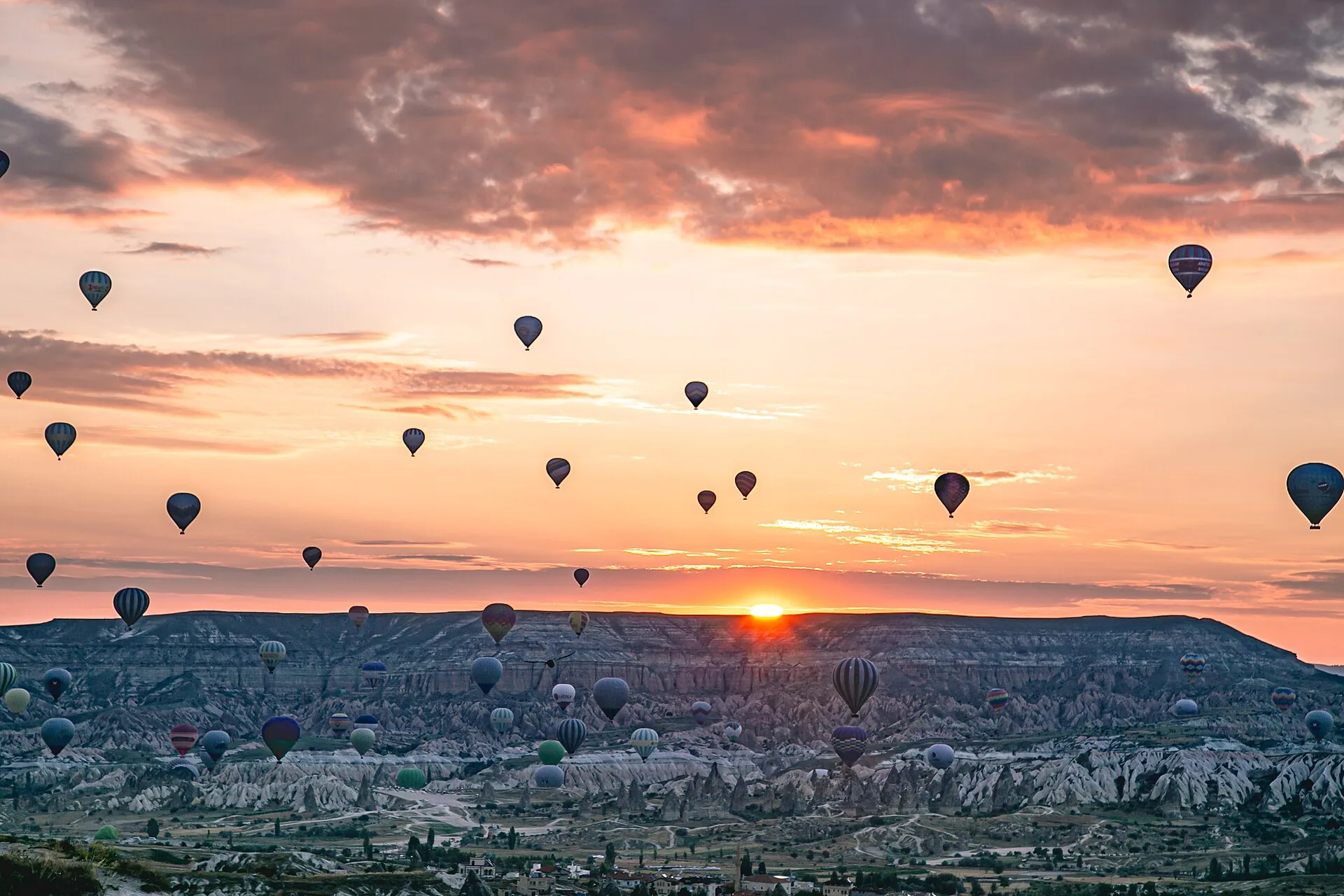 Dozens of hot air balloons floating over Cappadocia's eroded rock valleys at sunrise