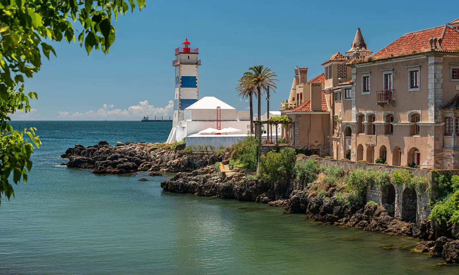 Santa Marta Lighthouse and Casa de Santa Maria overlooking the rocky coastline of Cascais, Portugal