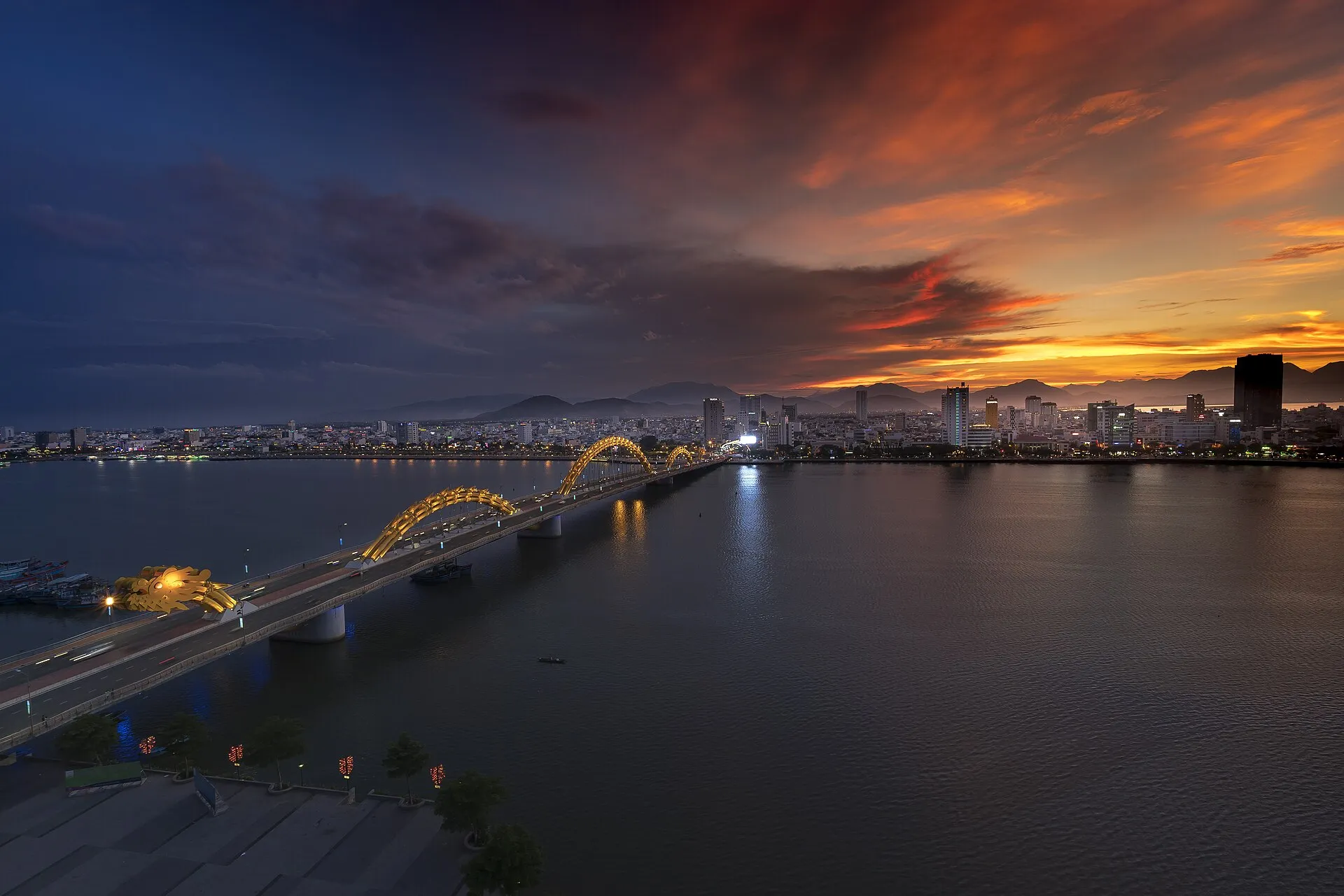 Dragon Bridge over the Han River at sunset with Da Nang city skyline and mountains