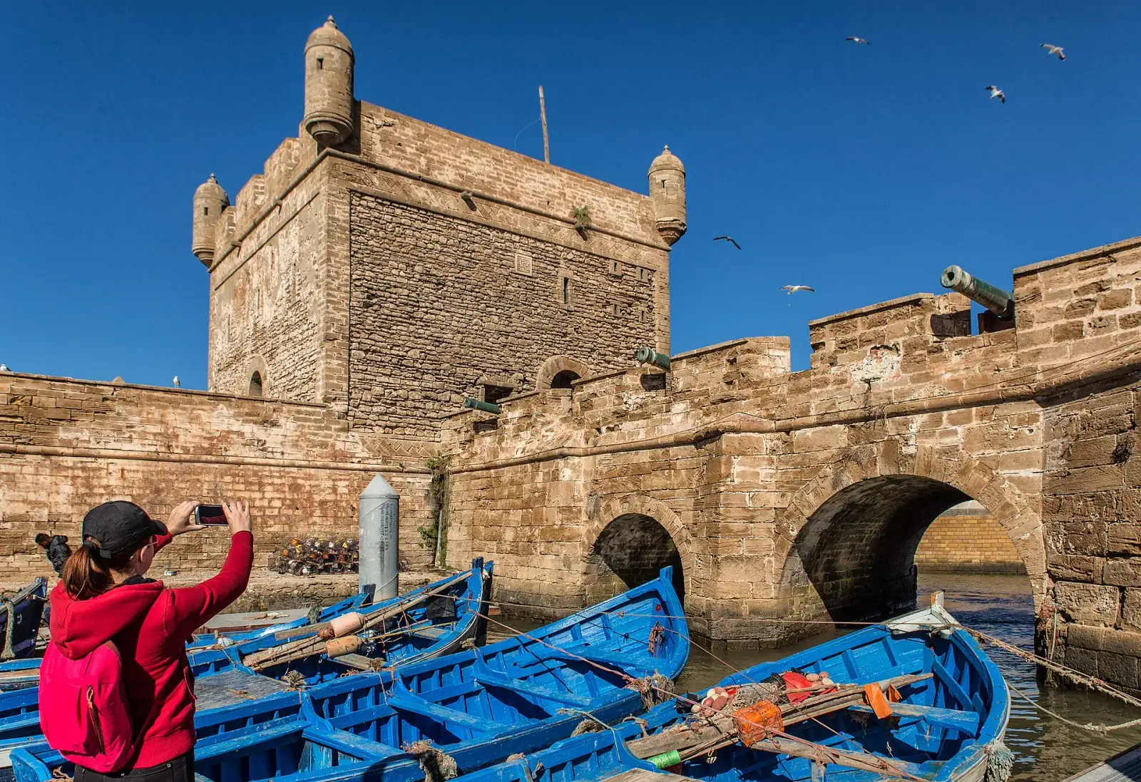 Blue fishing boats moored at the Sqala du Port fortress in Essaouira, Morocco