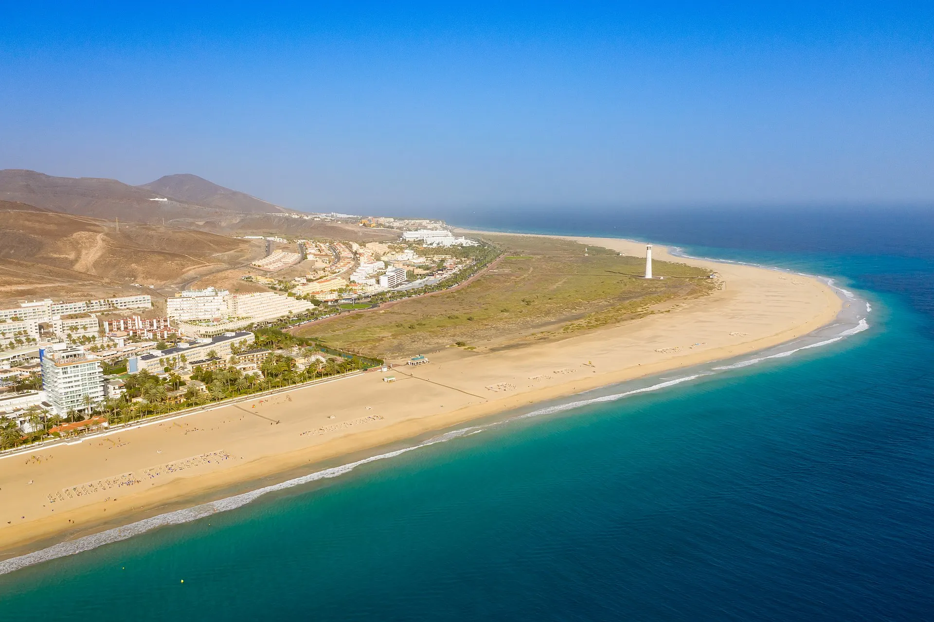 Aerial view of Jandia Beach and Playa del Matorral, Fuerteventura, with turquoise Atlantic water and the Morro Jable lighthouse