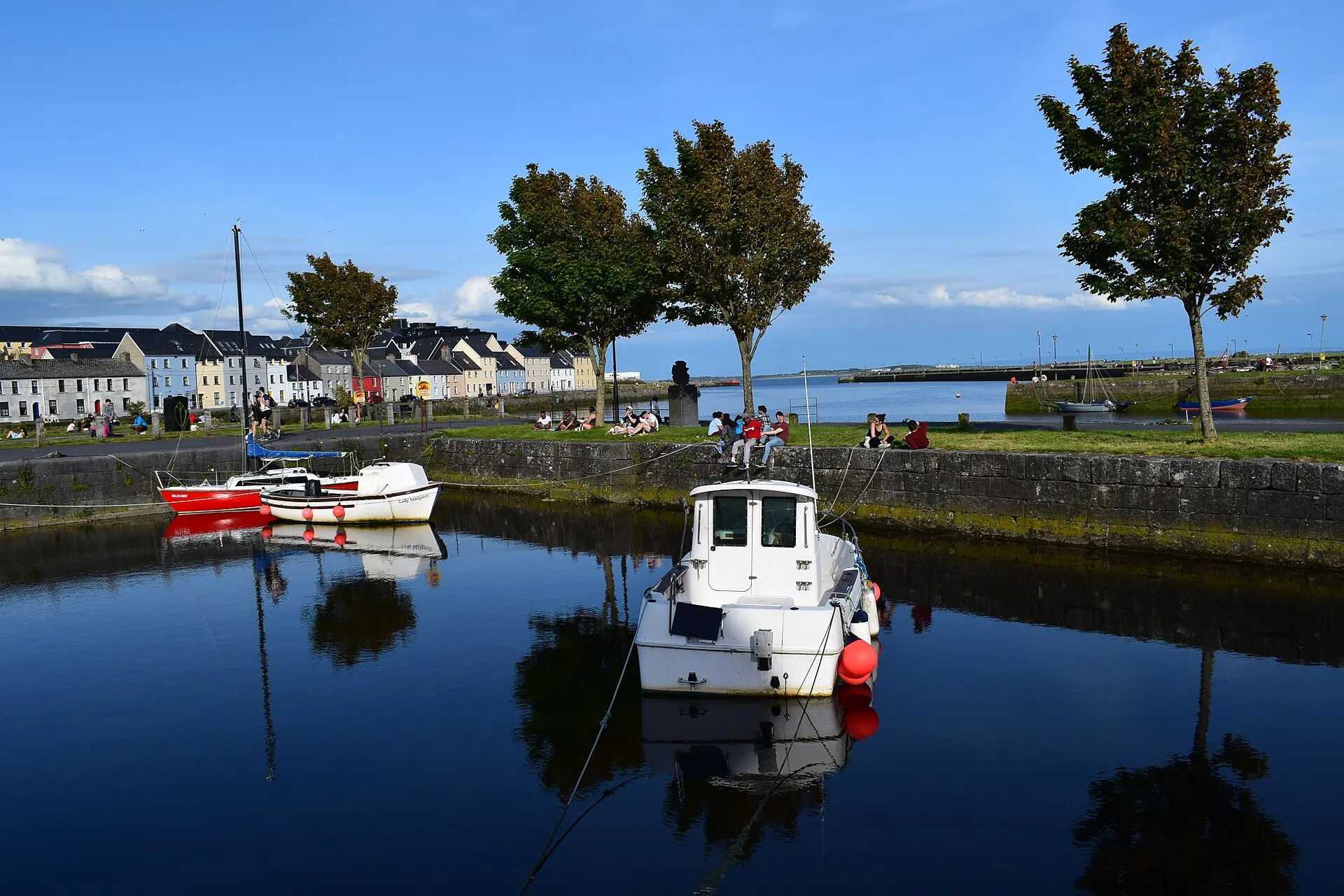 Boats moored in the Claddagh Basin, Galway, with colourful houses and Galway Bay in the background