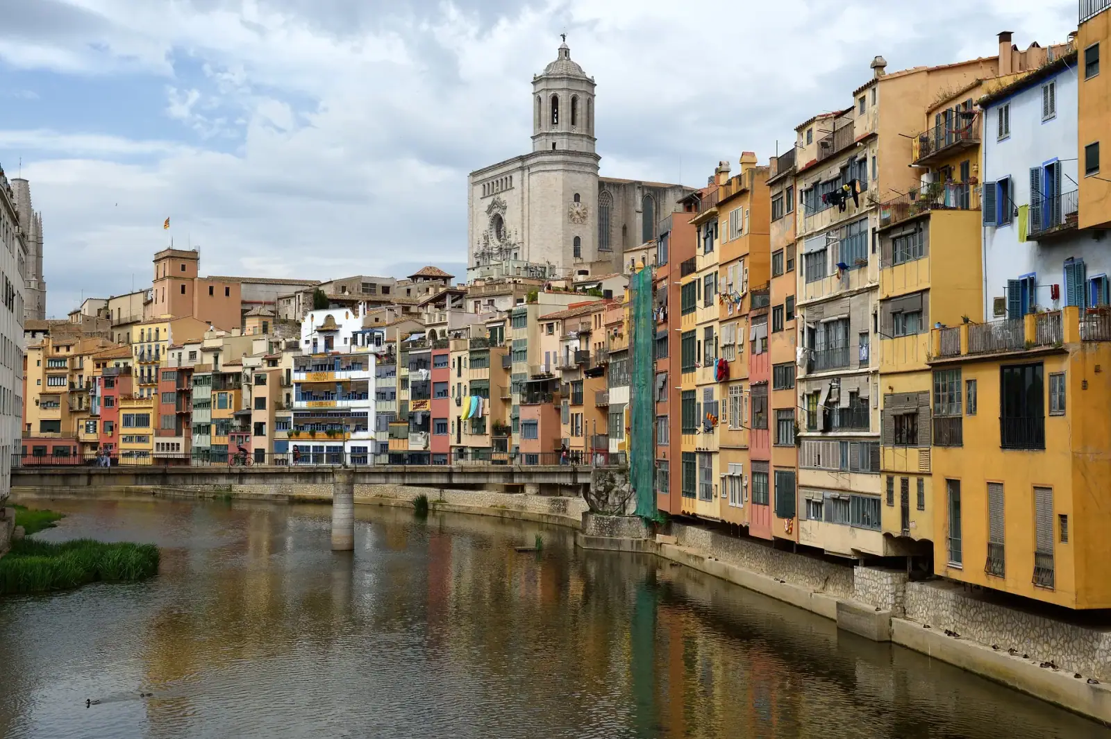 Colorful houses lining the Onyar River with Girona Cathedral rising above