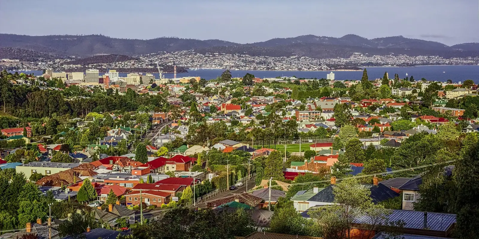Hobart cityscape seen from the foothills of Mount Wellington, with the Derwent River and mountains beyond