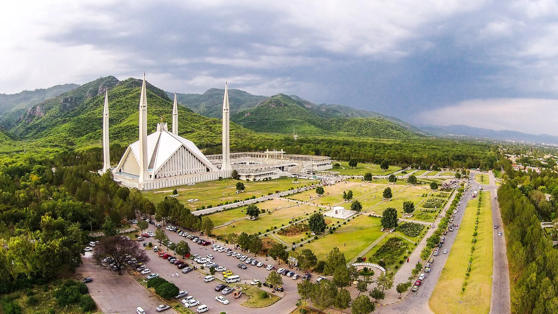 The white marble Faisal Mosque and its four minarets set against the green Margalla Hills in Islamabad, Pakistan.