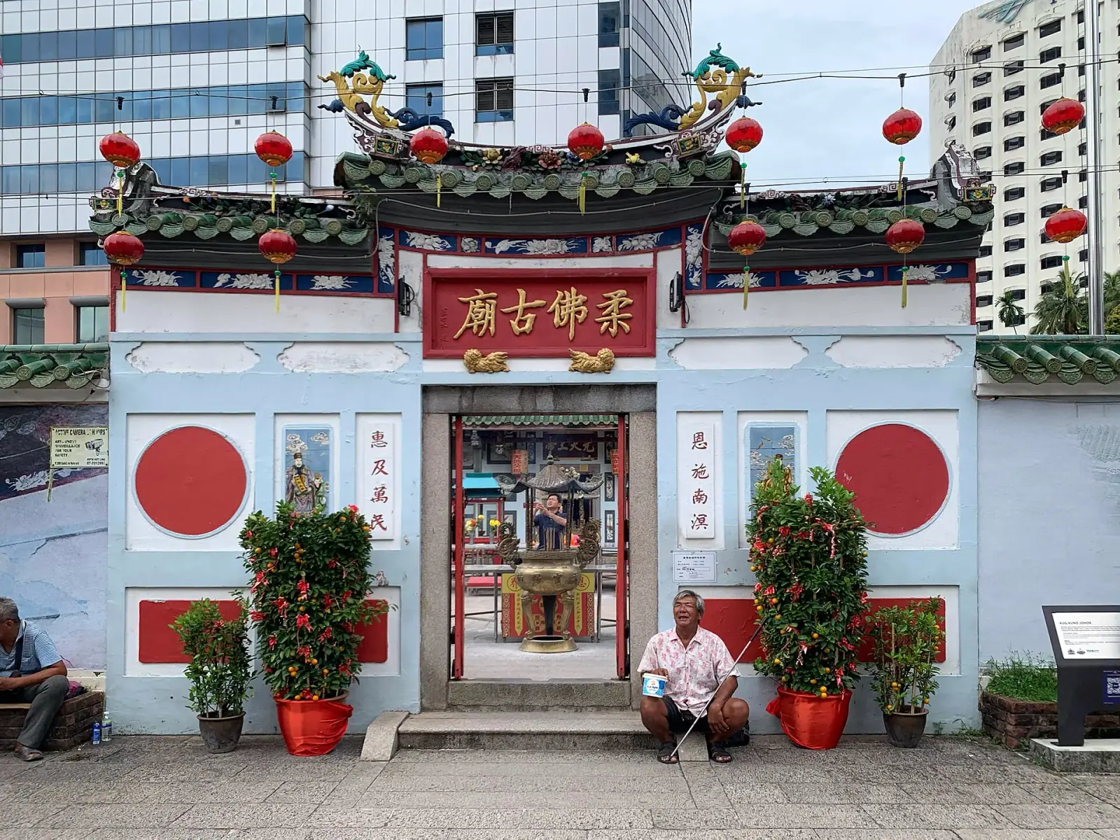 The Old Chinese Temple of Johor Bahru with red lanterns and modern skyscrapers behind