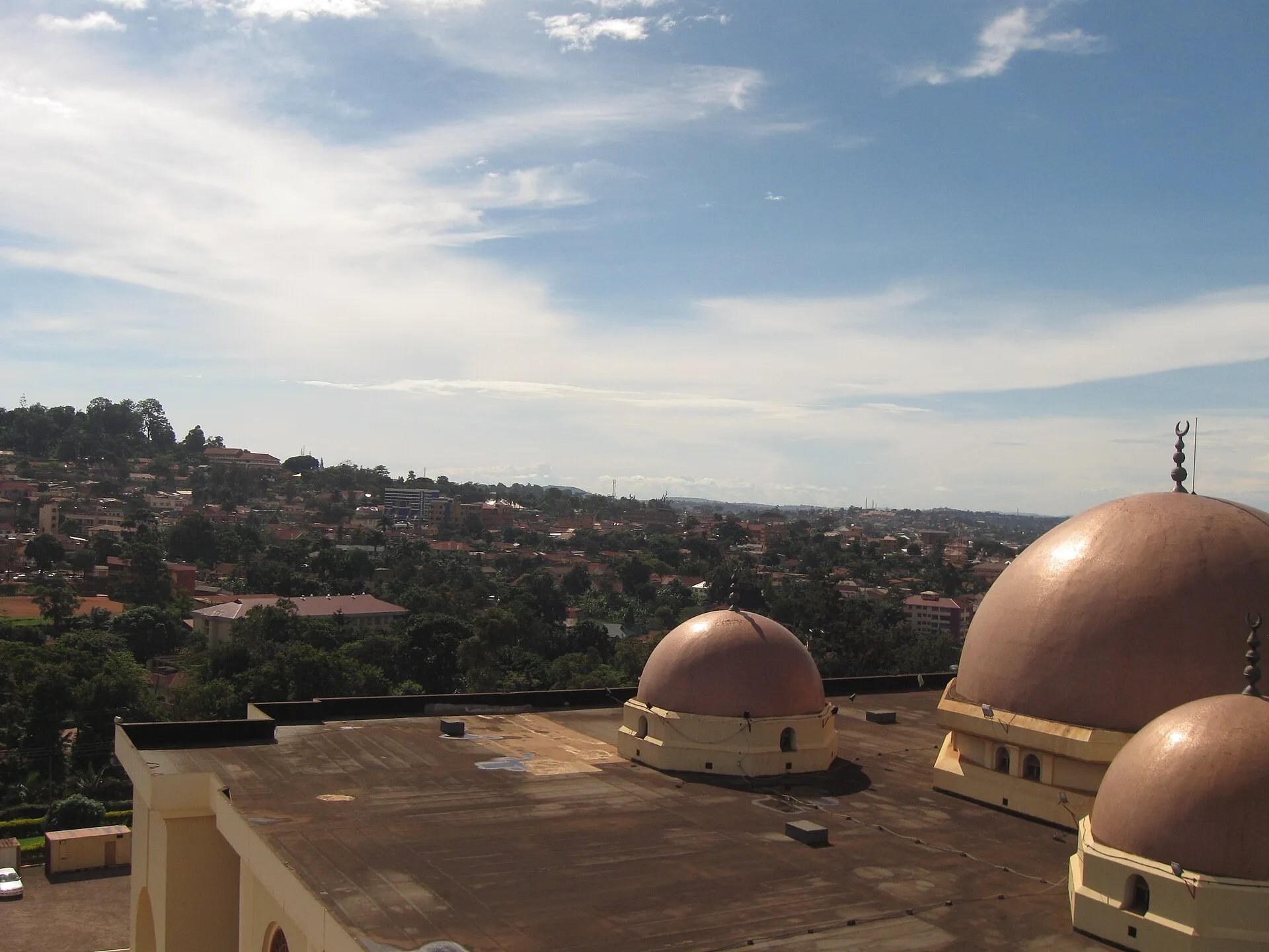 Kampala cityscape viewed from the Uganda National Mosque rooftop, with mosque domes in the foreground and the city spreading across green hills