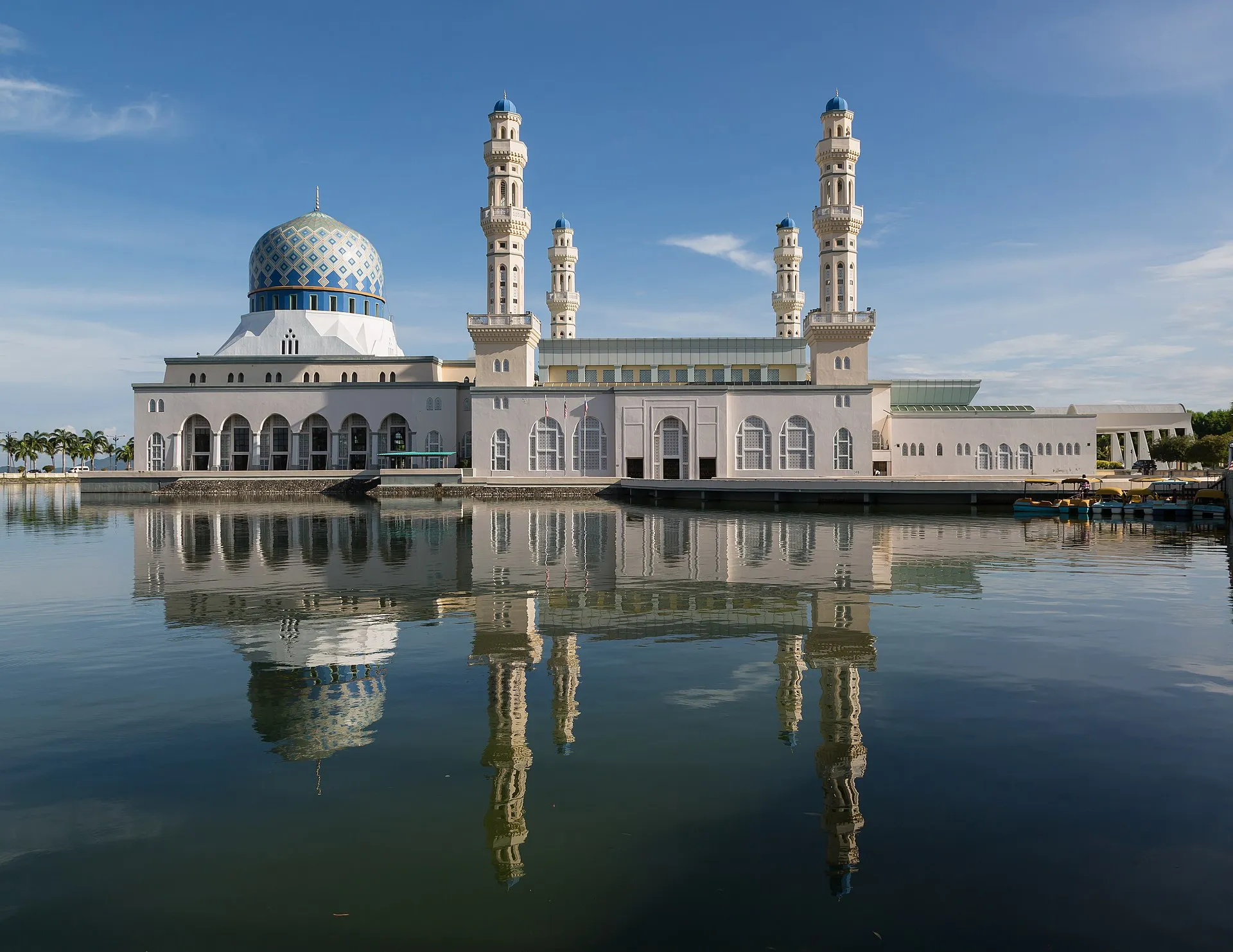 Kota Kinabalu City Mosque reflected in still water under blue sky