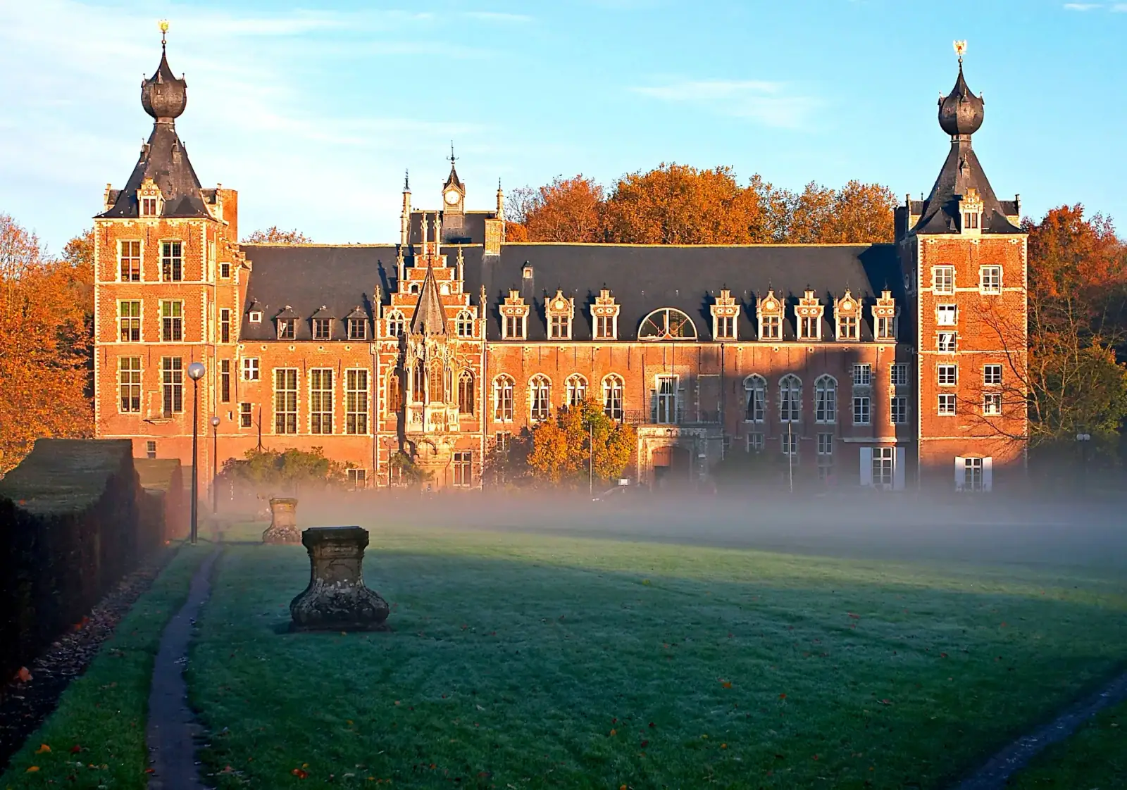Arenberg Castle at KU Leuven in morning mist with autumn foliage, Leuven, Belgium