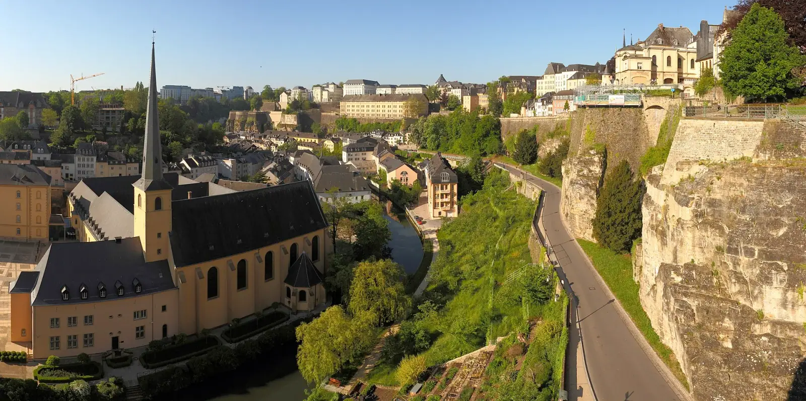 Panoramic view of Luxembourg City's Grund quarter with the Alzette river valley, fortress cliffs, and Saint-Jean-Baptiste church