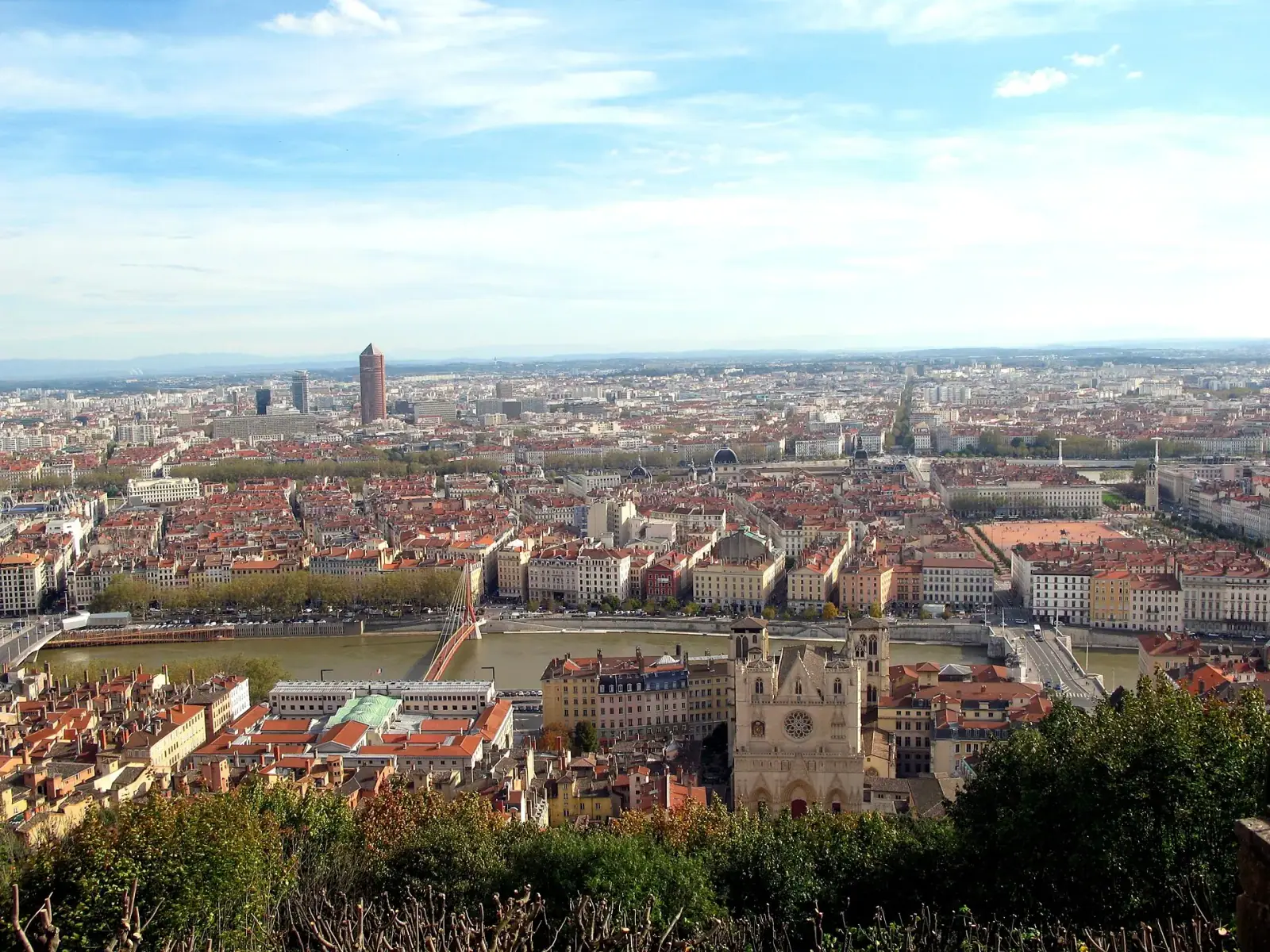 Panoramic view of Lyon from Fourvière hill showing Lyon Cathedral, the Saône river, and red-roofed Presqu'île with Tour Part-Dieu in the background