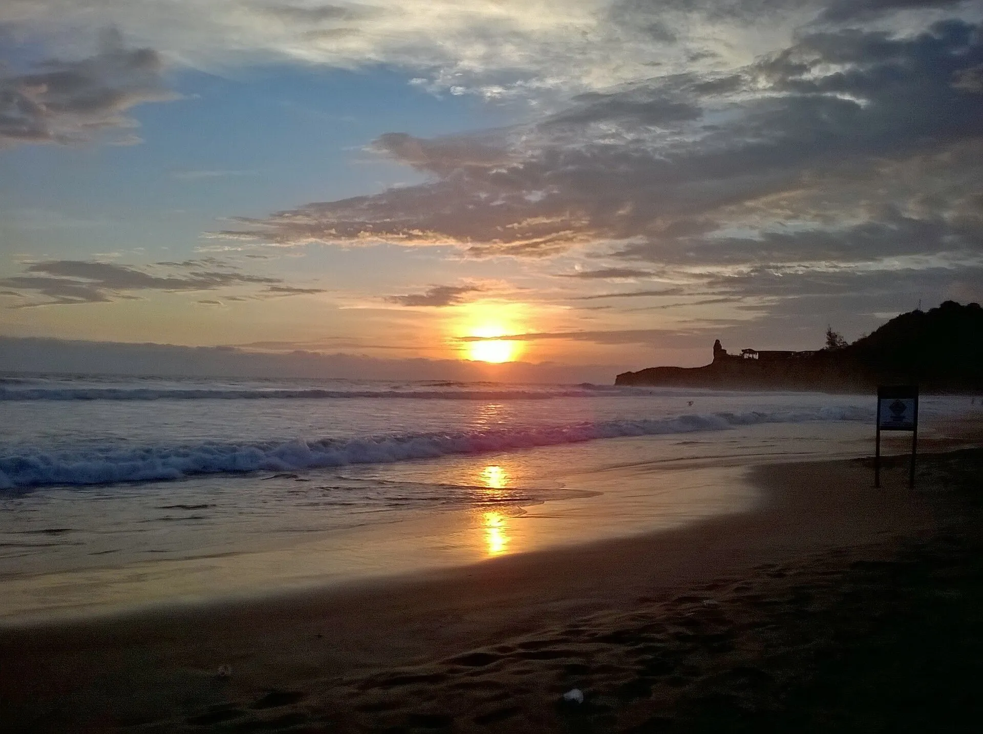 Sunset over Montañita beach with the iconic Punta de Montañita headland silhouetted on the right