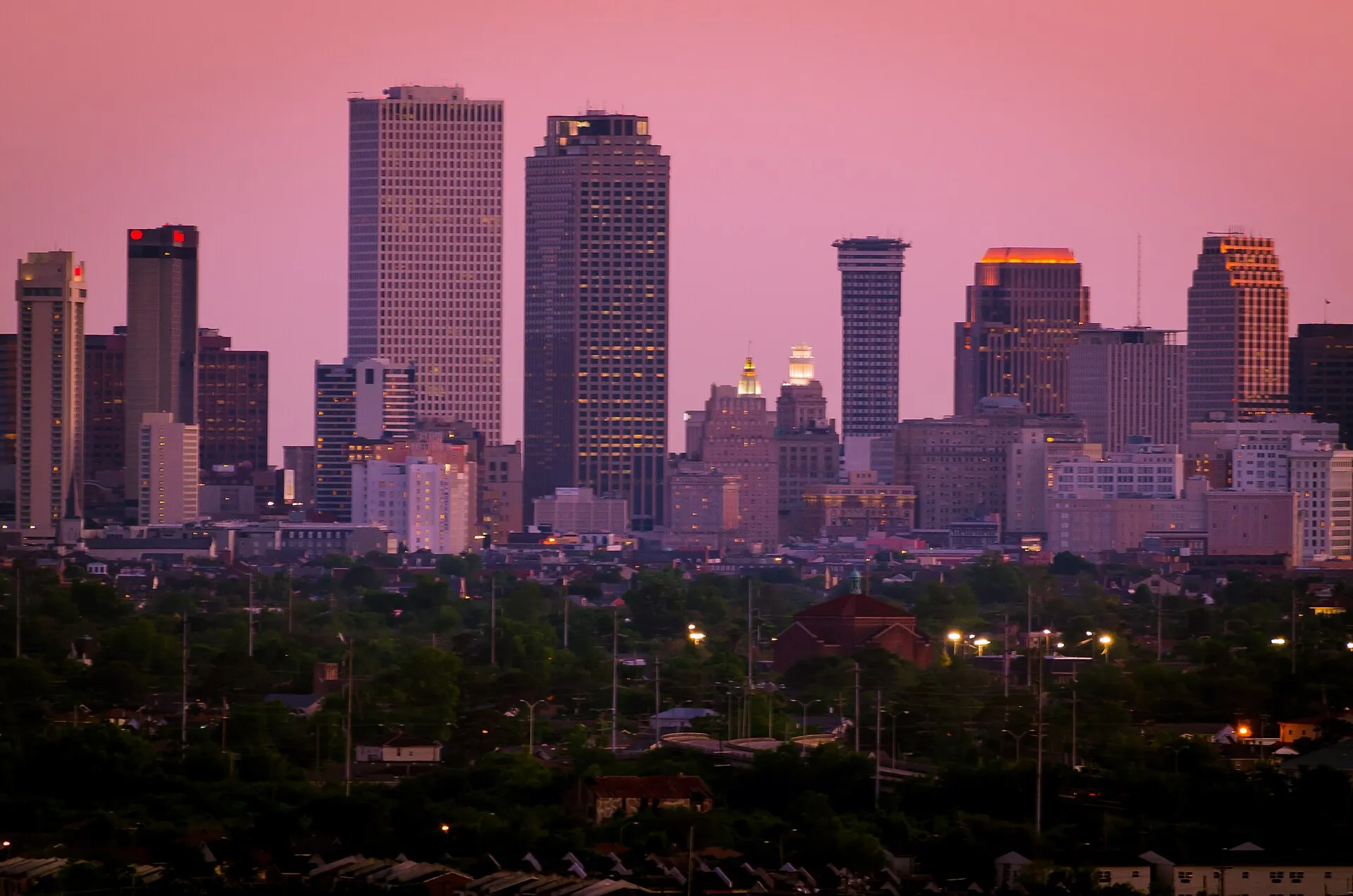 The downtown New Orleans skyline of high-rise towers glowing under a pink dusk sky