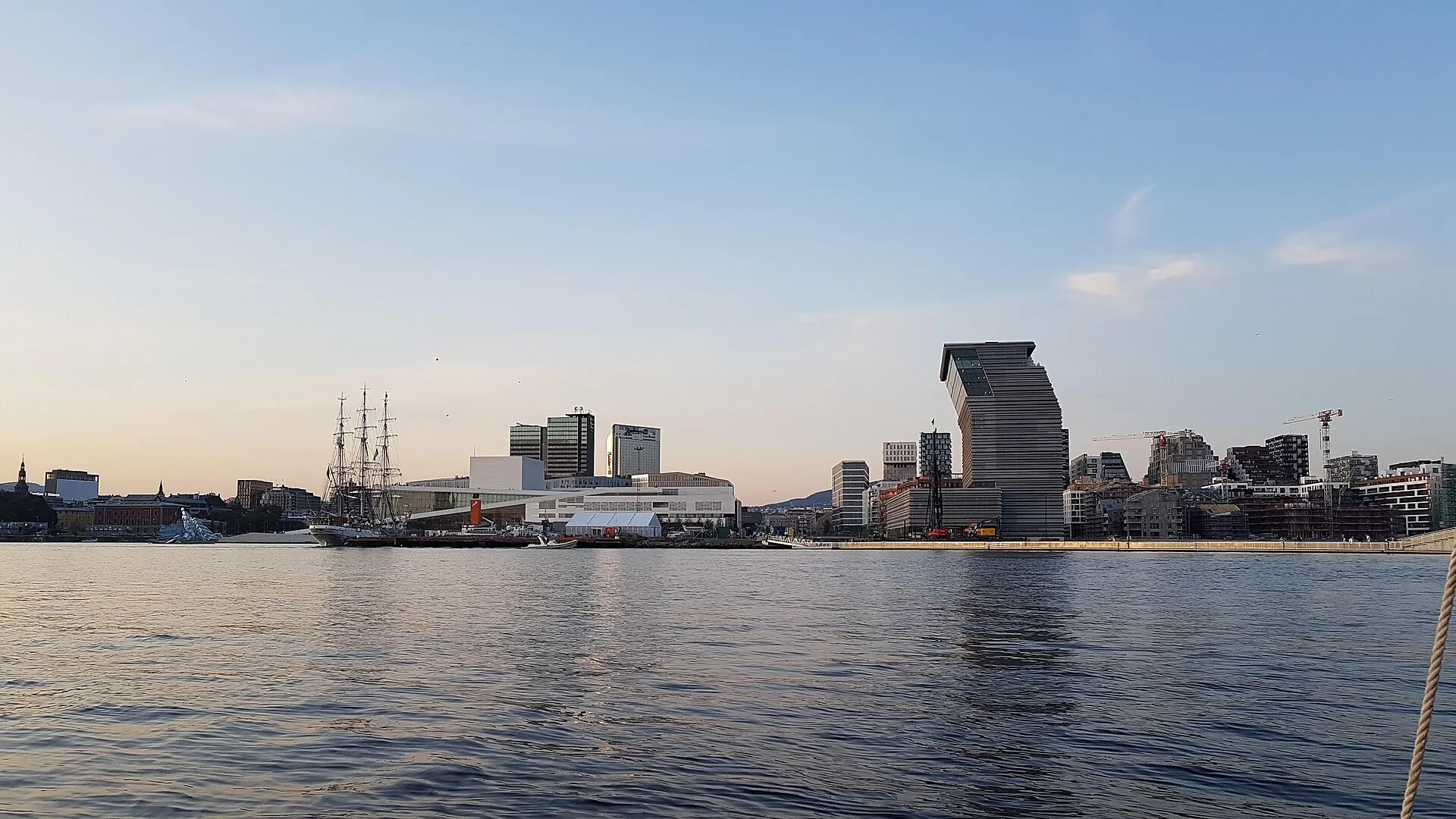 Oslo waterfront skyline at sunset with the Opera House and Munch Museum seen from the fjord