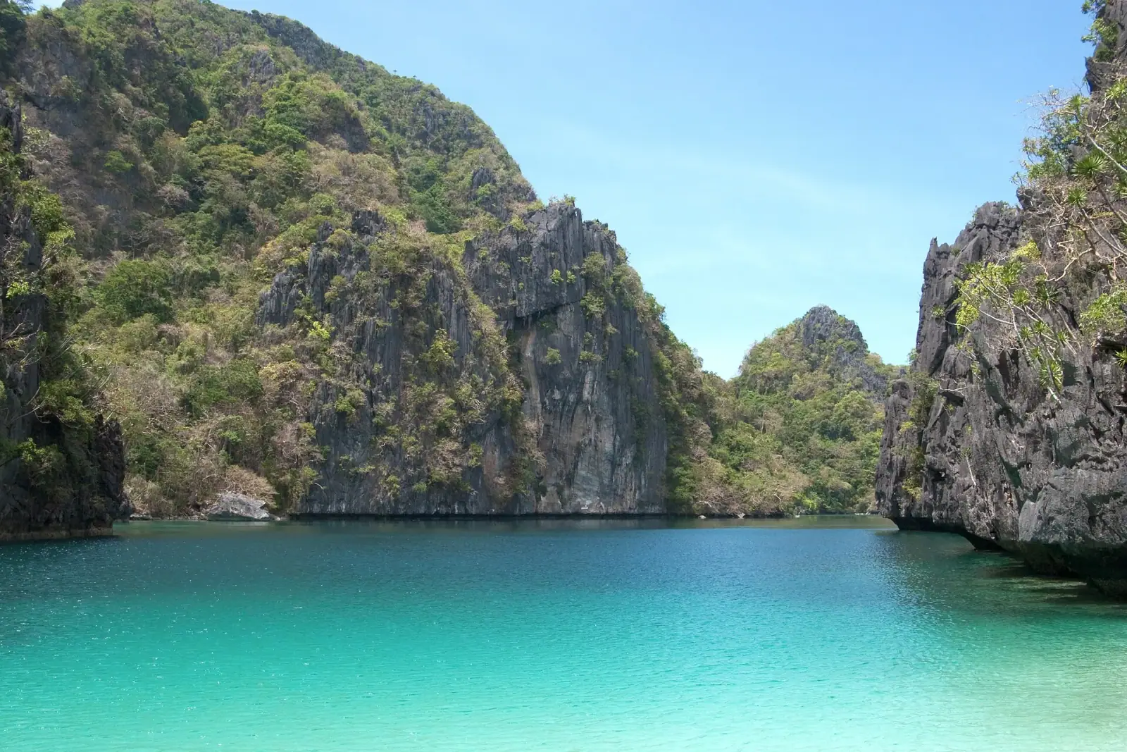 Turquoise lagoon surrounded by dramatic limestone karst cliffs at Bacuit Bay, El Nido, Palawan