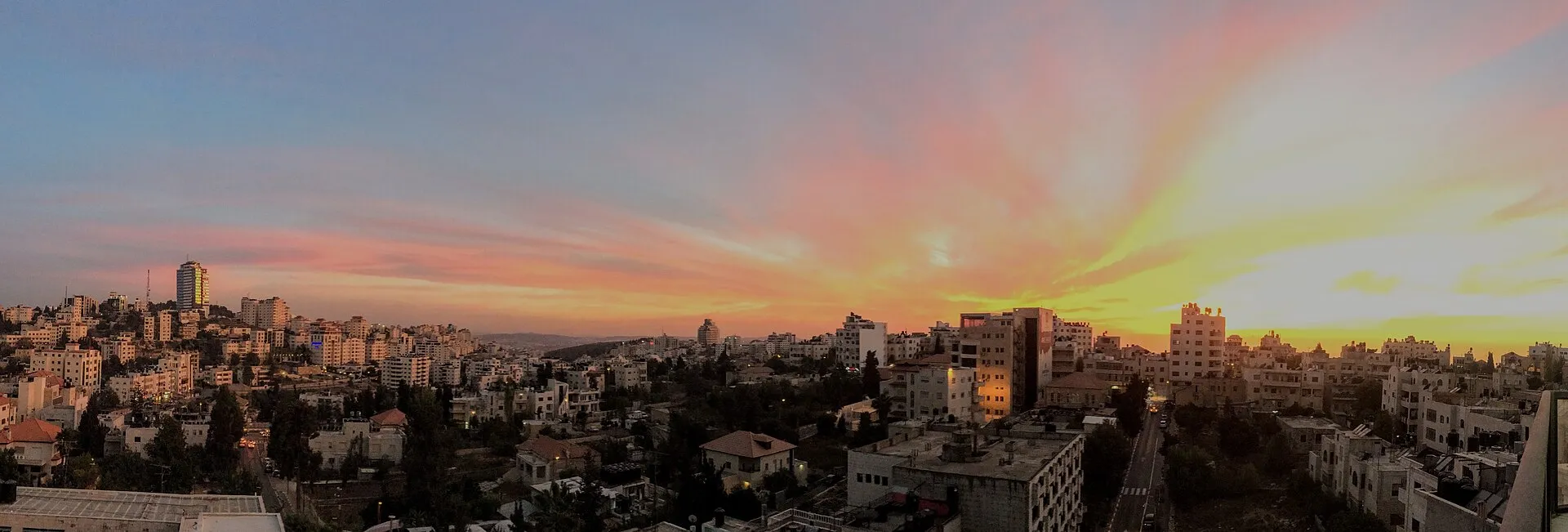 Panoramic view of Ramallah at sunset, showing the city's white limestone buildings spread across rolling hills
