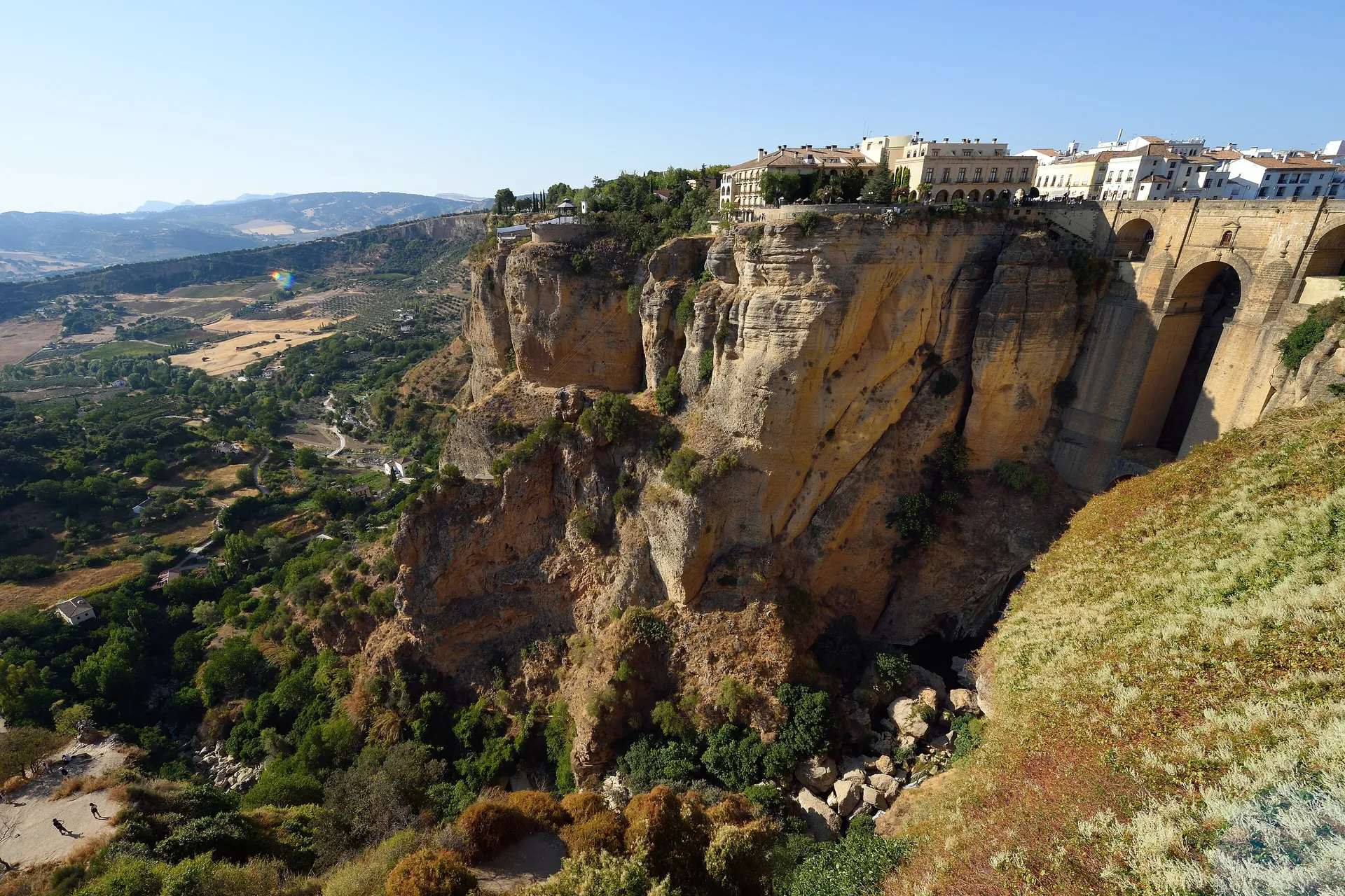 The deep El Tajo gorge splitting the town of Ronda, whitewashed houses perched on the sheer cliff-tops with the Puente Nuevo bridge spanning the ravine and the Andalusian countryside beyond