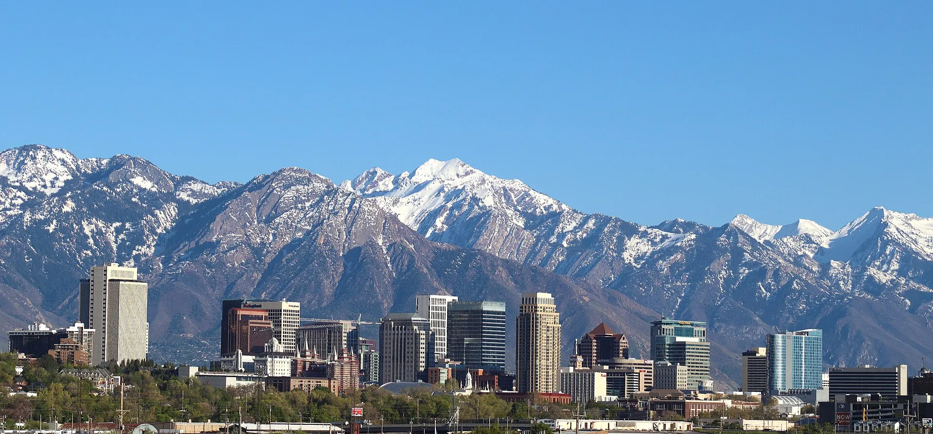 Downtown Salt Lake City with the snow covered peaks of the Wasatch Range rising behind it under a deep blue sky