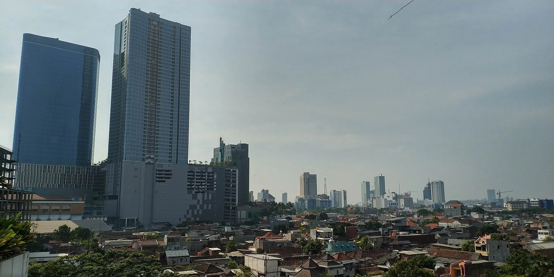 Surabaya CBD skyline with modern towers and traditional red-tile rooftops viewed from JW Marriott hotel