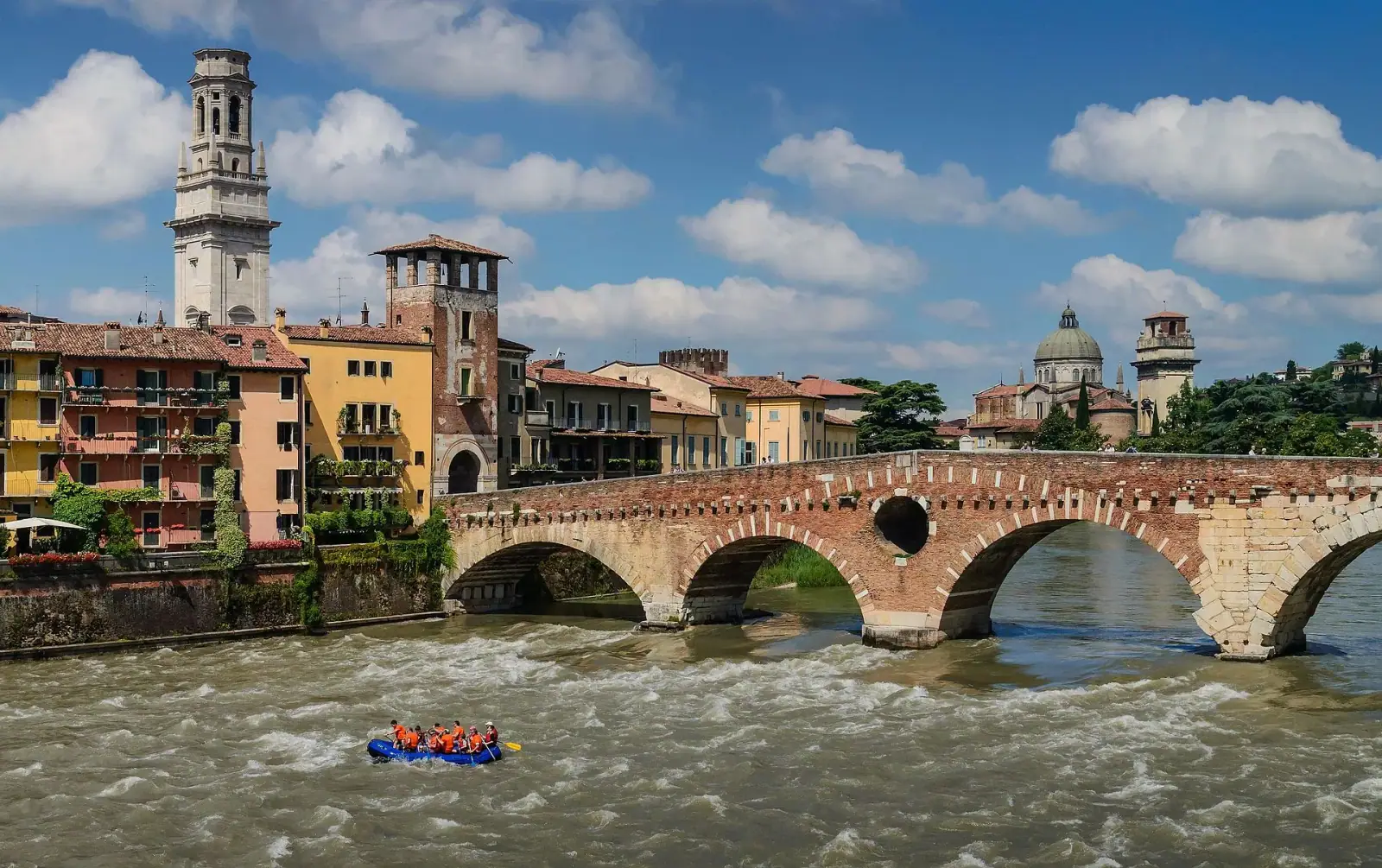 Ponte Pietra Roman bridge over the Adige river with Verona Cathedral bell tower and colourful buildings behind, on a sunny day