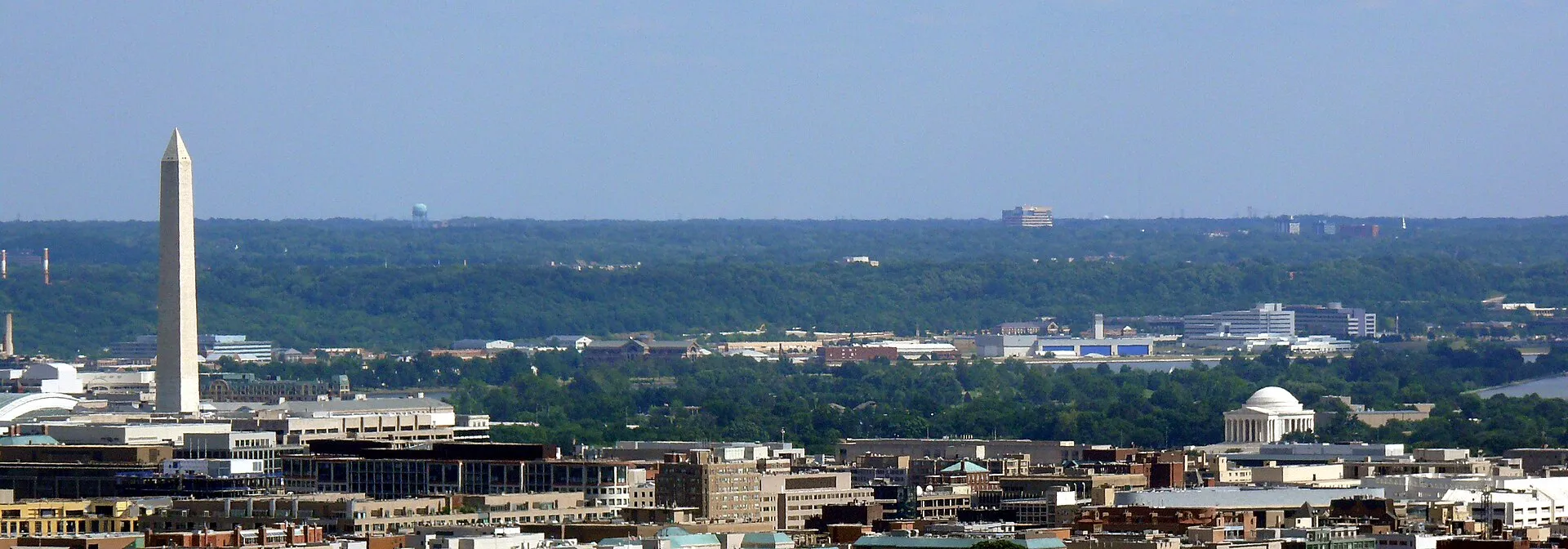 A wide daytime view of Washington D.C. with the Washington Monument and the domed Jefferson Memorial rising above the city