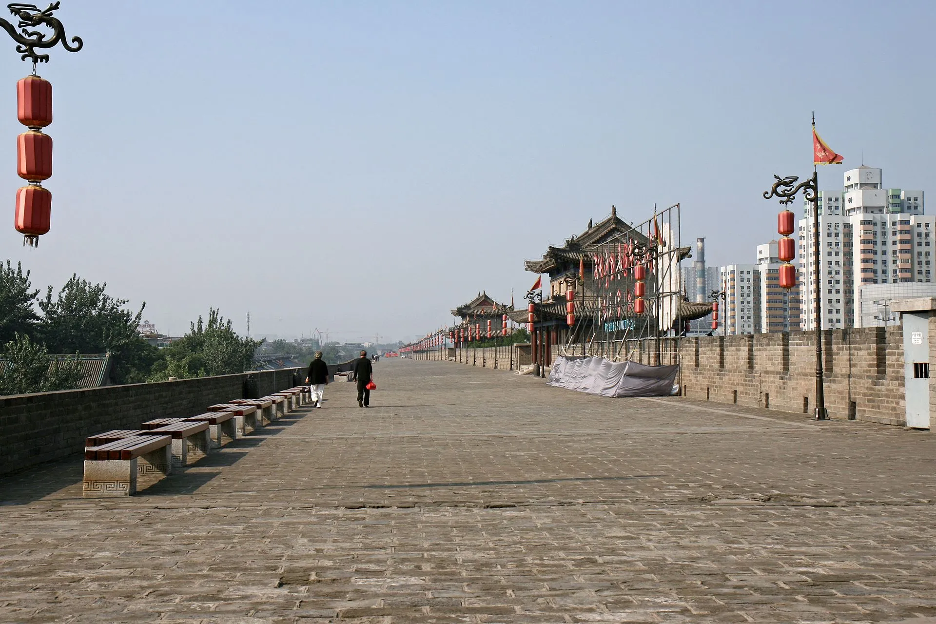 Xian city wall promenade with traditional gate tower and lanterns, modern skyline behind