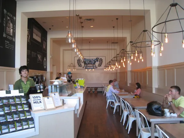Interior of Phil and Sebastian Coffee Roasters with branded coffee bags on counter and industrial pendant lighting