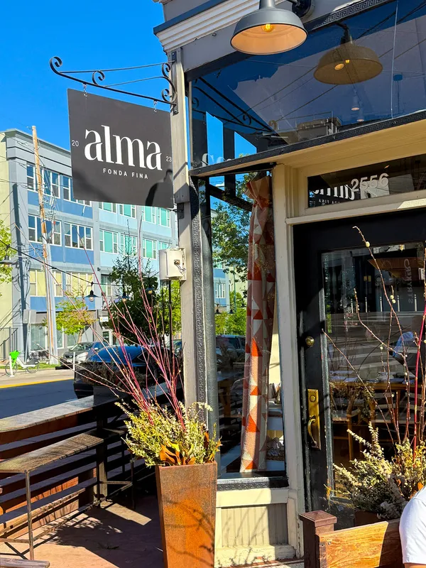 Exterior of Alma Fonda Fina restaurant in Denver showing the hanging sign and entrance