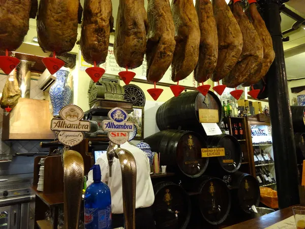 Interior of Bodegas Castaneda with hanging hams and wine barrels, Granada
