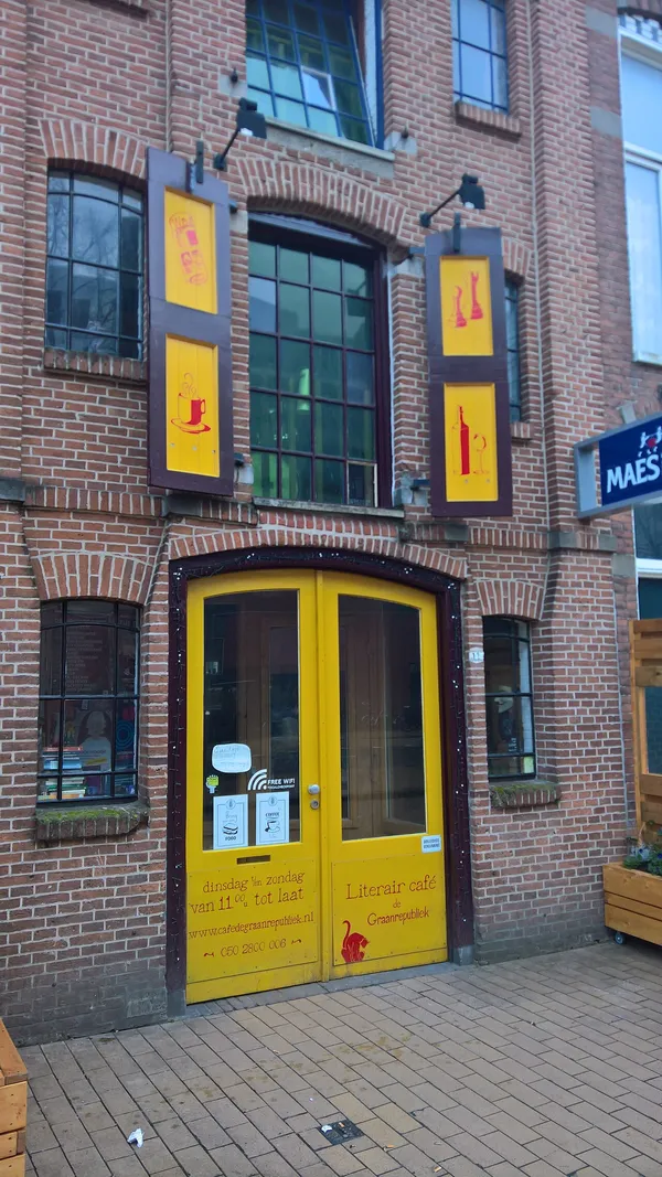 Yellow-painted brick storefront of Literair Cafe de Graanrepubliek in Groningen