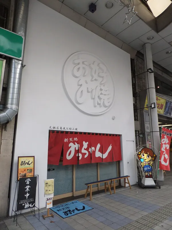 Exterior of Micchan Shintenchi okonomiyaki restaurant in Hiroshima, with red noren curtain