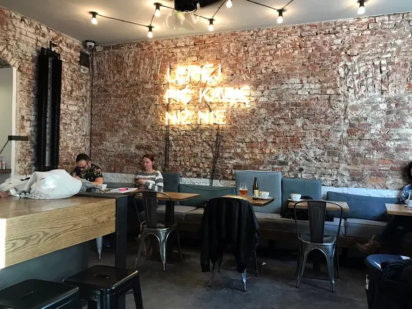 Interior of Wesoła Cafe, Krakow, with exposed brick wall and neon sign