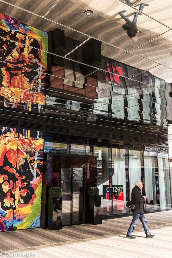 Exterior entrance of citizenM hotel in Shoreditch, London, with colorful mural art and reflective glass facade