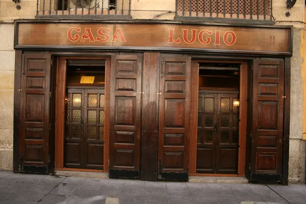 Facade of Casa Lucio restaurant in Madrid showing the classic wooden entrance doors and red Casa Lucio sign