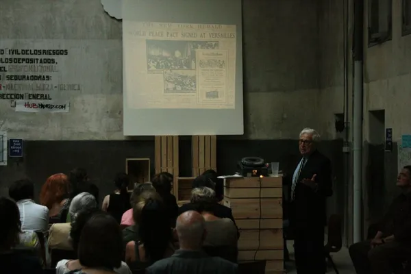 Interior of Impact Hub Madrid during a community lecture event, showing the industrial space with exposed concrete walls