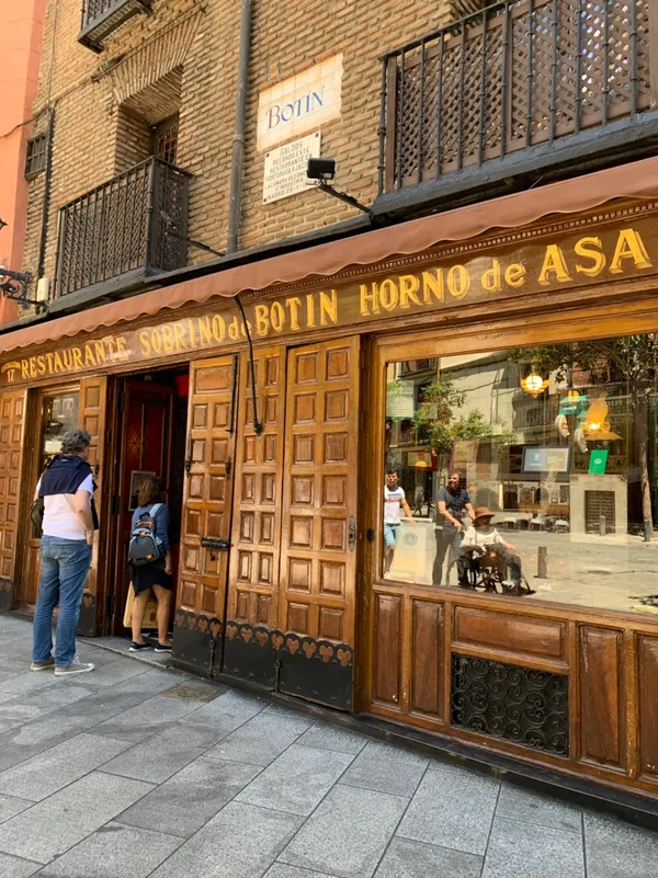 Facade of Sobrino de Botin restaurant in Madrid with historic wooden doors and golden lettering on the awning