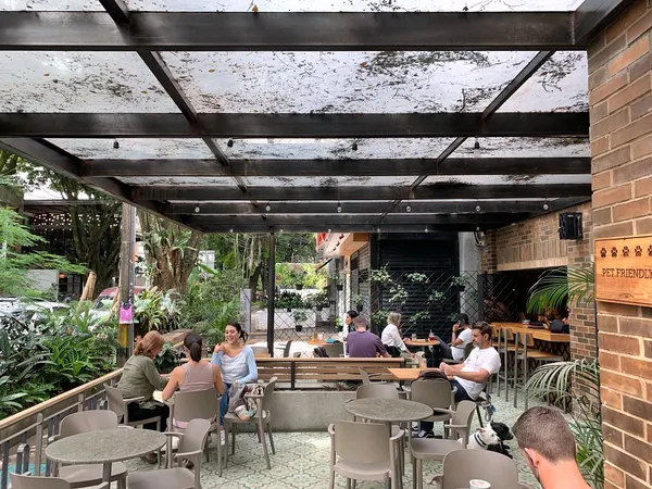 Outdoor terrace seating area at Pergamino Café, Medellín, with glass roof and tropical plants