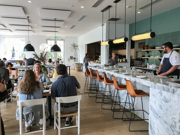 Bright dining room at Henrietta Red Nashville with marble oyster bar counter, leather stools, and open kitchen