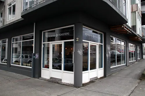 Reykjavik Roasters coffee shop exterior at dusk, dark grey corner building with branded signage
