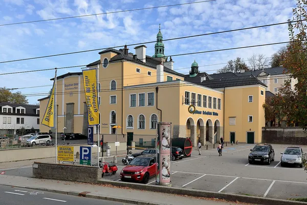 Augustinerbräu Kloster Mülln exterior with yellow Augustiner banners and monastery church spires, Salzburg