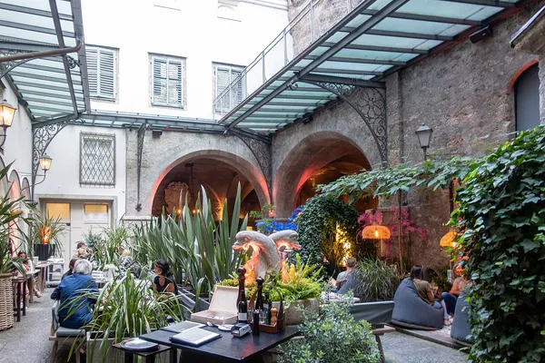 St. Peter Stiftskulinarium courtyard restaurant with stone arches and lush greenery, Salzburg