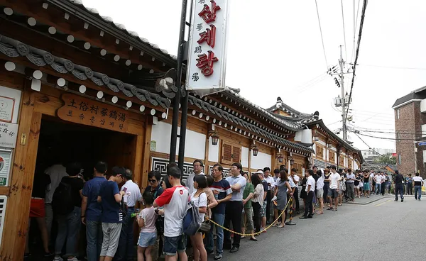 Long queue outside Tosokchon Samgyetang restaurant in Seoul, its traditional hanok building bearing the restaurant name in Korean and Chinese characters