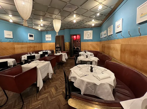 Interior dining room of Restaurang Sturehof, Stockholm, with blue walls, leather banquettes and white-draped tables