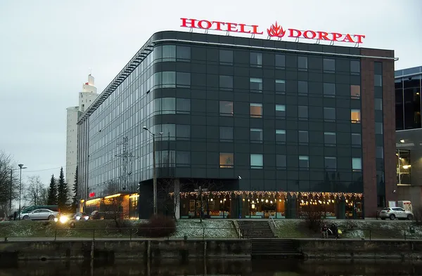 Dorpat Hotel exterior at dusk showing the modern glass building with red illuminated sign, Tartu