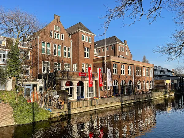 Stayokay hostel building on the Haagse Trekvliet canal in The Hague, with red Stayokay banners on the brick facade